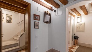 A hallway with a staircase, framed pictures on the wall, and a wooden ceiling beam. - SAN SILVESTRO HOUSE VENICE (Venezia)
