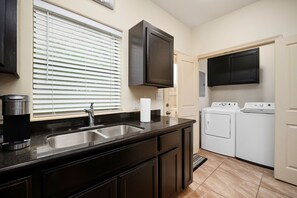 A kitchen with a black countertop, stainless steel sink, and a built-in washer and dryer. - Nest at Hummingbird 3 w King bed free parking  Patio (Pharr)