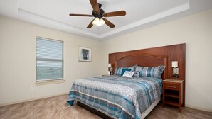 A bedroom with a bed, a wooden headboard, a nightstand, a ceiling fan, and a window with blinds. - Nest at Hummingbird 3 w King bed free parking Patio. (Pharr)
