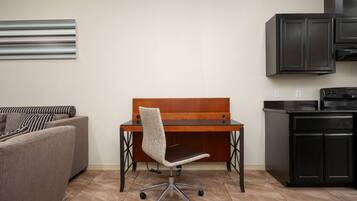 Un espacio habitable compacto con un sofá, un escritorio de madera con silla y una kitchenette.