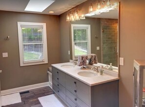 A bathroom with two sinks, a large mirror, and a shower area. - Lakefront. Spectacular Mountain and Lake Views/Dock/Private Cove. Gentle Slope. (LaFollette)