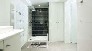 Une salle de bain moderne avec une douche, un meuble-lavabo blanc et un sol carrelé.