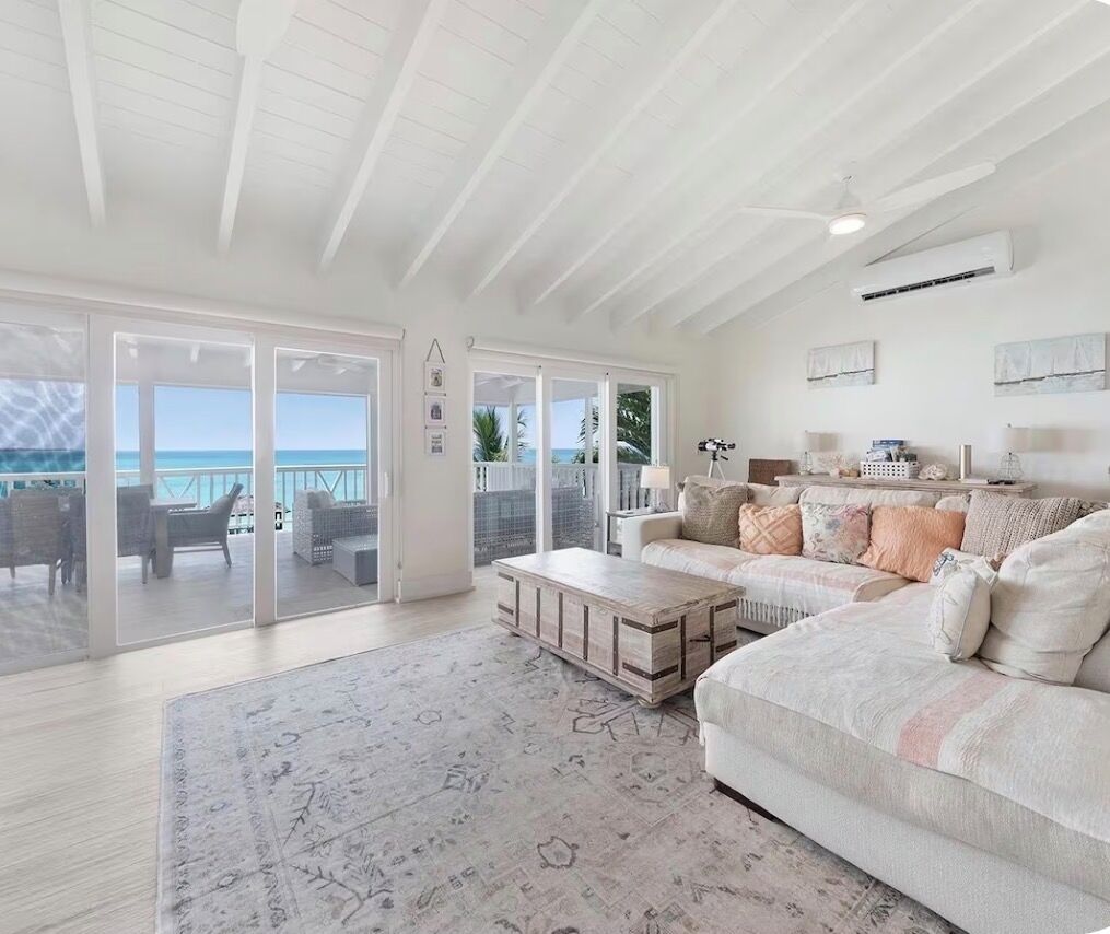 Een ruime woonkamer met een groot raam met uitzicht op zee, een gezellige bank en een houten bijzettafeltje.