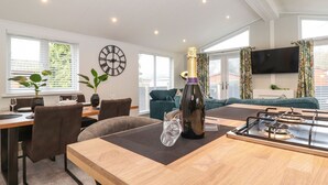 Una sala de estar moderna con comedor, un reloj de pared grande y un televisor montado en la pared.