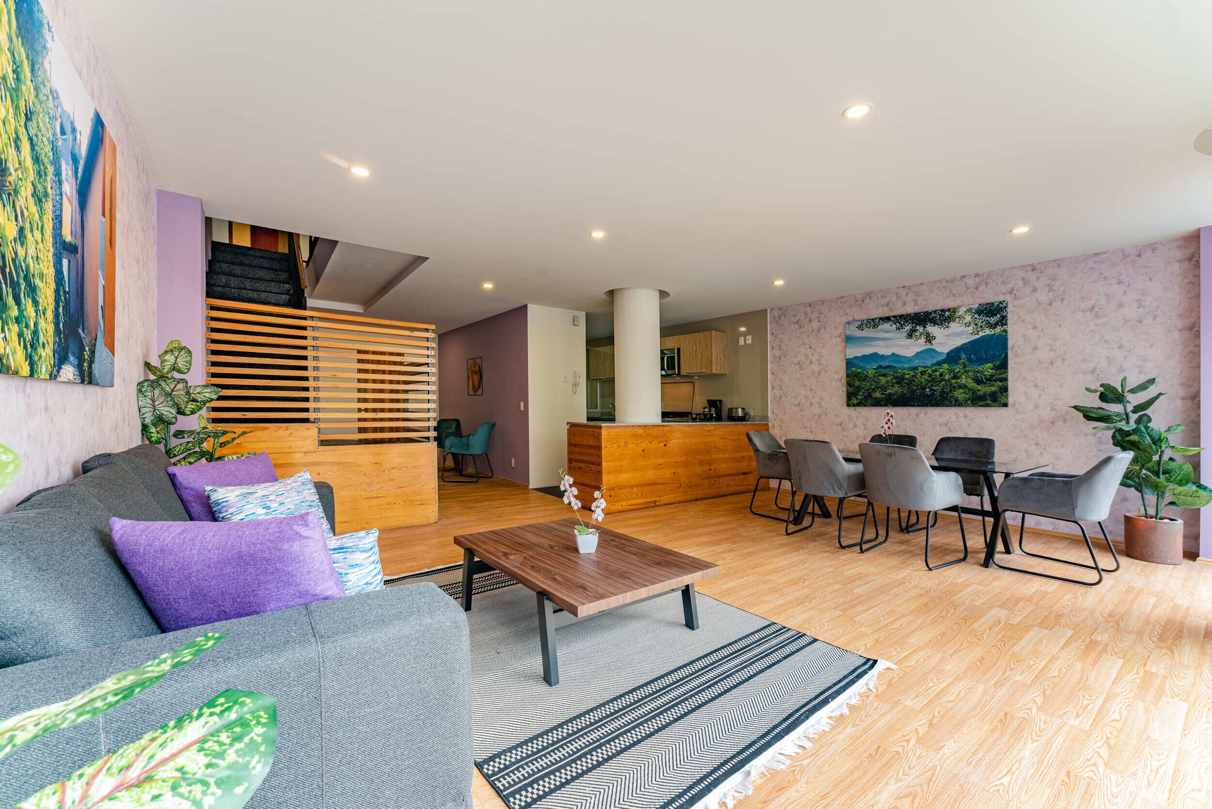 Een moderne woonkamer met een bank, salontafel en eethoek.