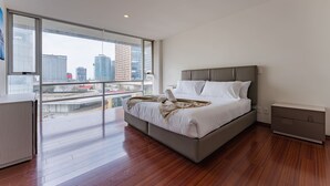 A modern bedroom with a large window, a bed, a bedside table, and a built-in bench. - Antara apartments by VH (Mexico City)