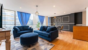 A modern living room with two sofas, a coffee table, and a wooden dining table. - Antara apartments by VH (Mexico City)