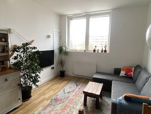 Cozy living space with a minimalist design, featuring a sofa, coffee table, and flat-screen TV.