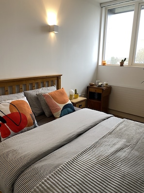 Restful retreat with a comfortable bed, bedside table, and window offering a view.