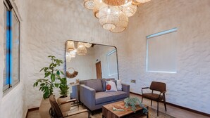 Un salon comprenant un canapé, des fauteuils, une table basse et un grand miroir.