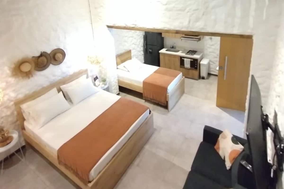 Ein Schlafzimmer mit zwei Betten, einer Schlafcouch, einem Fernseher und einer Küchenzeile.