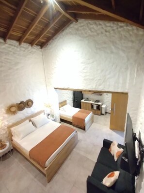 Ein Schlafzimmer mit zwei Betten, einer Schlafcouch, einem Fernseher und einer Küchenzeile.