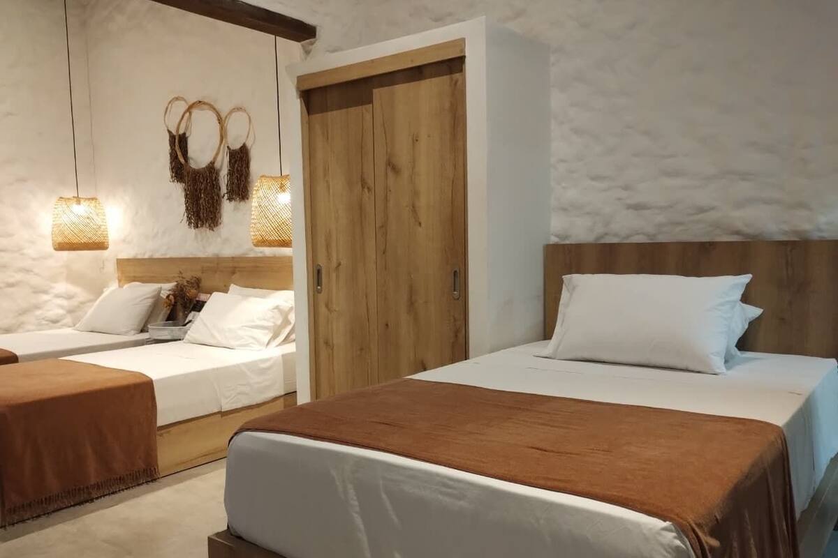 Ein Schlafzimmer mit zwei Betten, einem Holzschrank und Pendelleuchten.