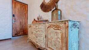 Un meuble en bois de style vintage, doté de tiroirs, d’un miroir décoratif et d’une bouteille posée sur le dessus.