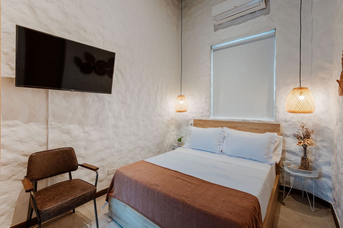 Ein Schlafzimmer mit Bett, Stuhl, Fernseher und Fenster.