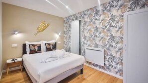 A bedroom with a bed, a nightstand, a wall-mounted radiator, and a tropical leaf-patterned wallpaper. - 2.Luxueux Duplex#3Bedrooms#FullEquipped#République (Paris)