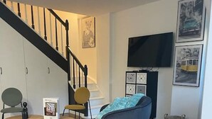 A living room with a staircase, a TV mounted on the wall, and a colorful rug. - 2.Luxueux Duplex#3Bedrooms#FullEquipped#République (Paris)