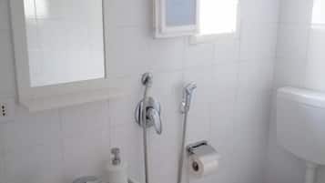 A bathroom with a white sink, mirror, toilet, and a small window.