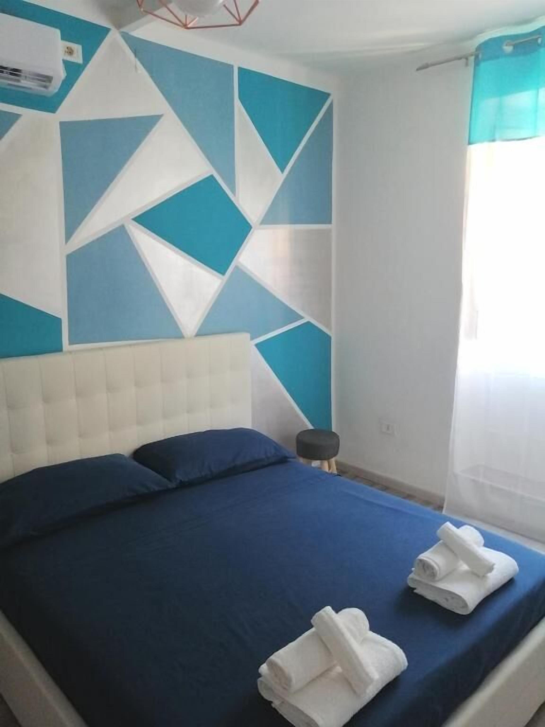 Una cama con una colcha azul, dos almohadas y dos toallas dobladas.