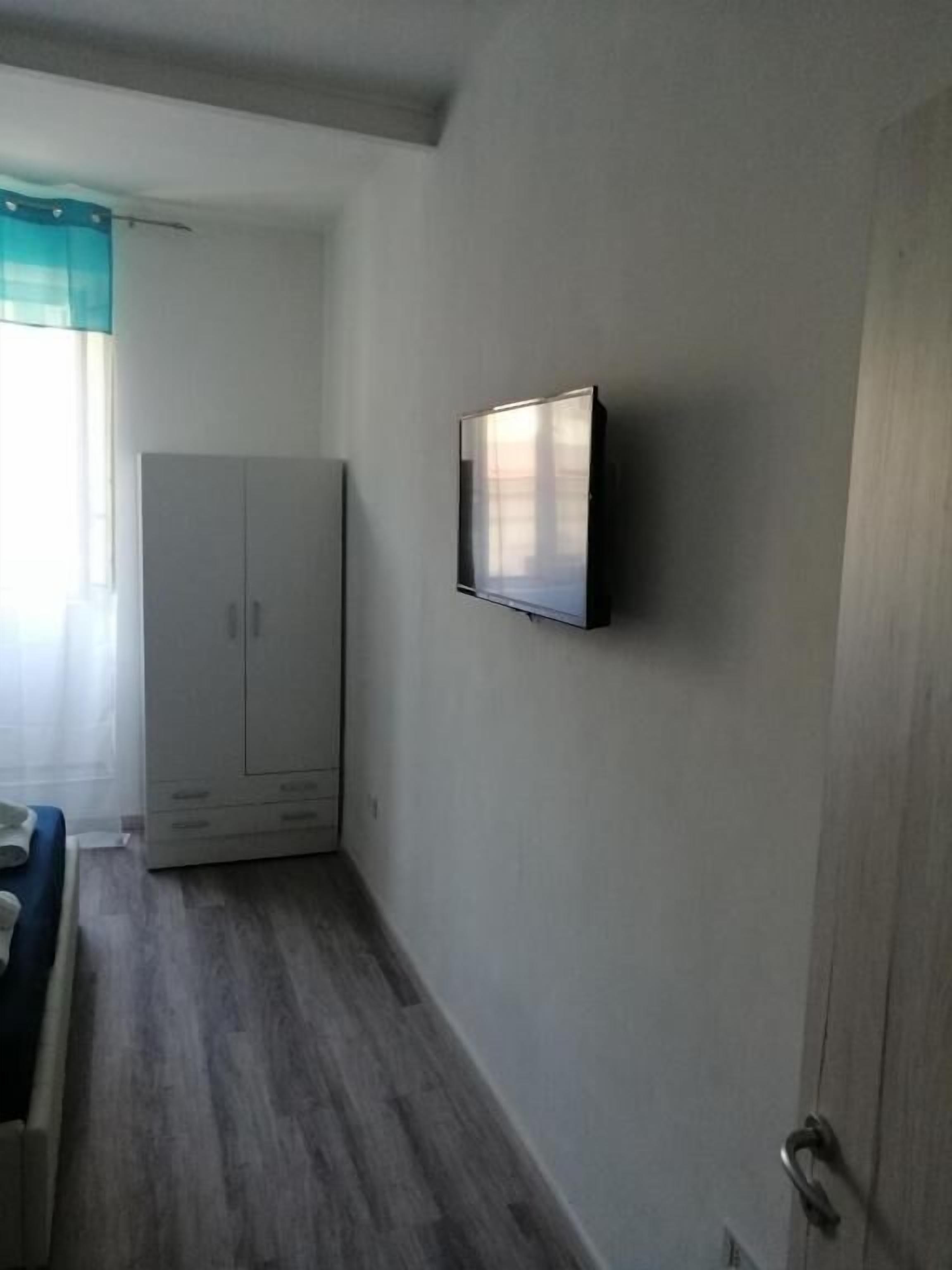 Una habitación con armario, televisor montado en la pared y una puerta.