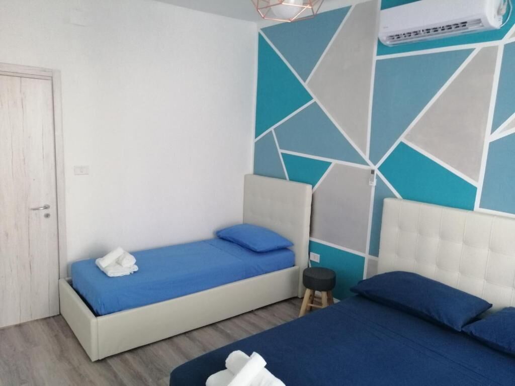 A bedroom with two beds, a white door, and a geometric wall design.