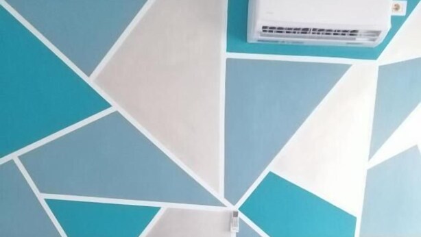 Un dormitorio con dos camas, un taburete pequeño y un aire acondicionado de pared.