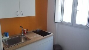 Una cocina compacta con lavamanos, estufa y armarios.