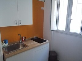A compact kitchen with a sink, stove, and cabinets.
