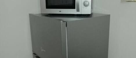 Un refrigerador de acero inoxidable con un microondas incorporado encima.