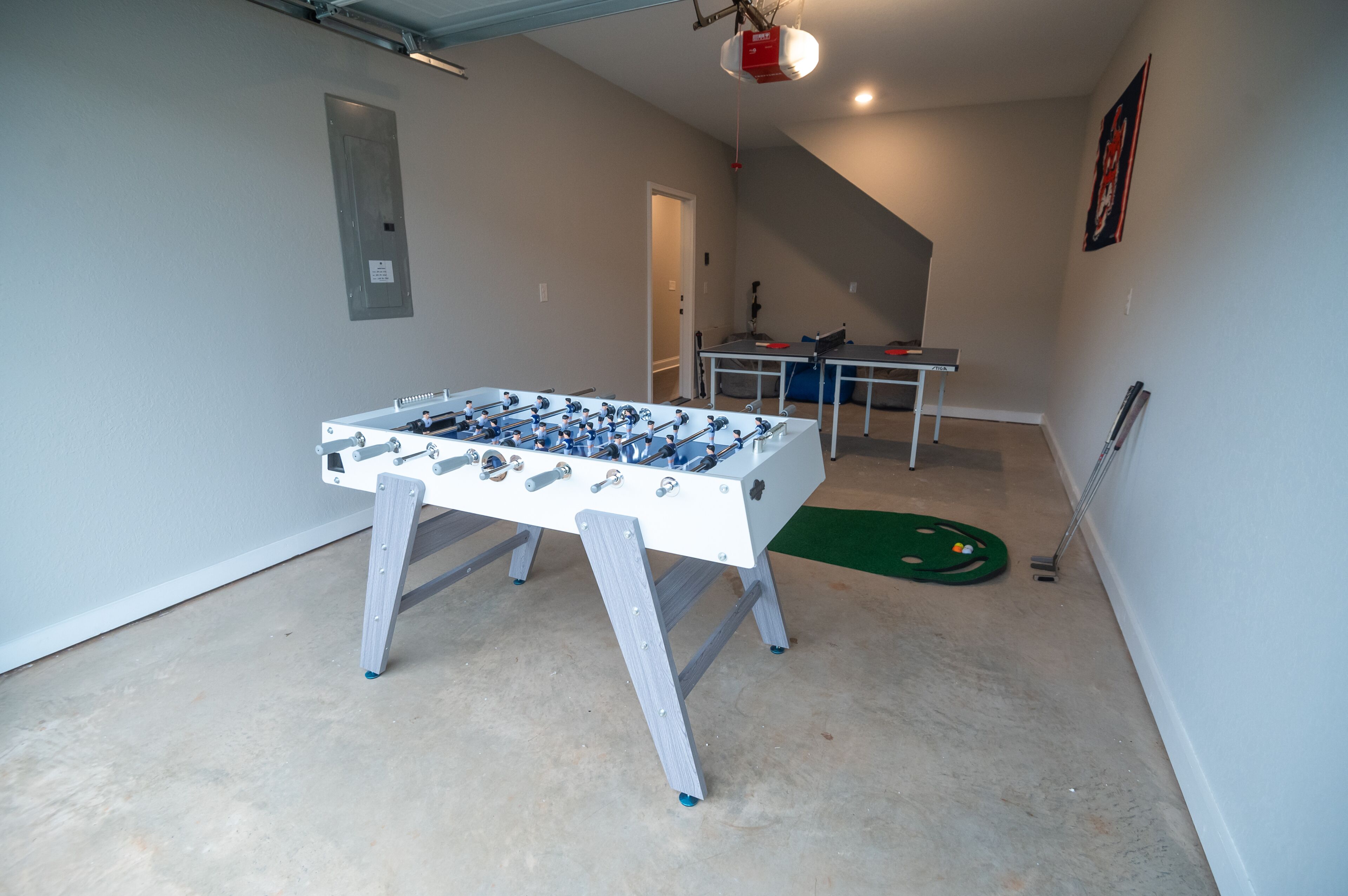 Une pièce équipée d’un baby-foot, d’une table de ping-pong et d’un tapis vert.