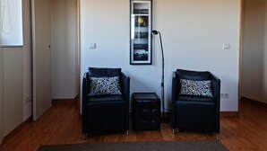 Une pièce avec deux chaises noires dotées de coussins à motifs de mosaïque, un lampadaire et un tableau encadré accroché au mur.