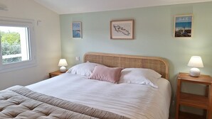 Een slaapkamer met een bed, twee nachtkastjes, een raam en wanddecoratie.