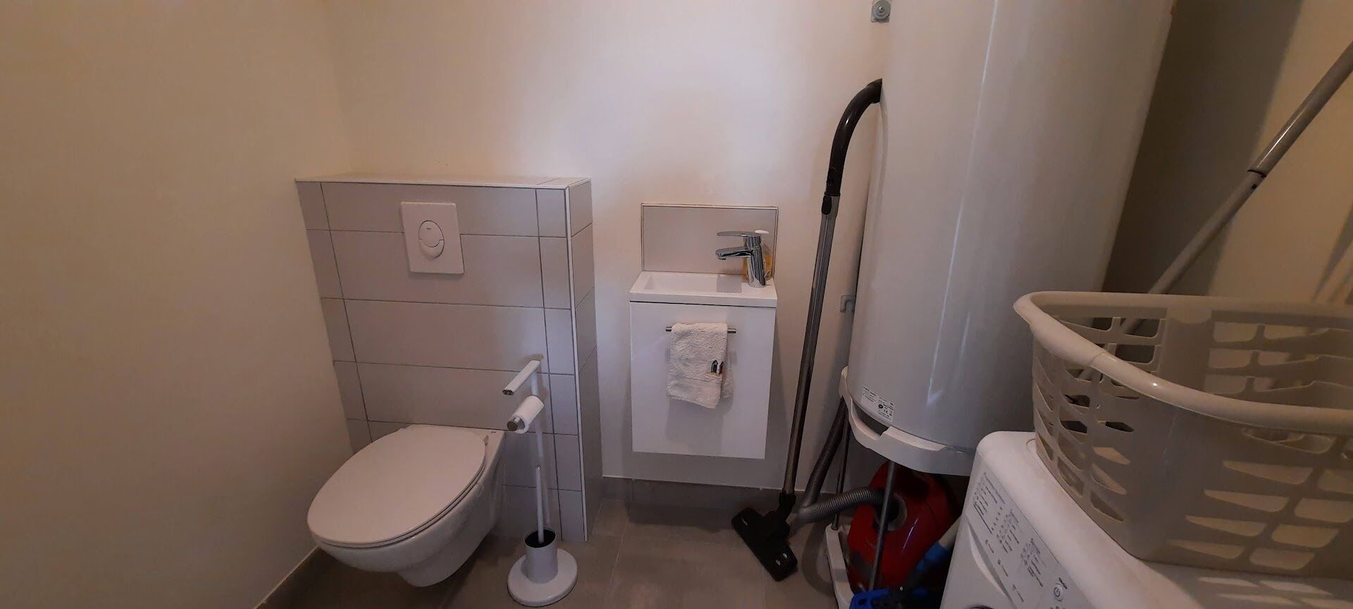 Une petite salle de bain comprenant des toilettes, un lavabo et un lave-linge.