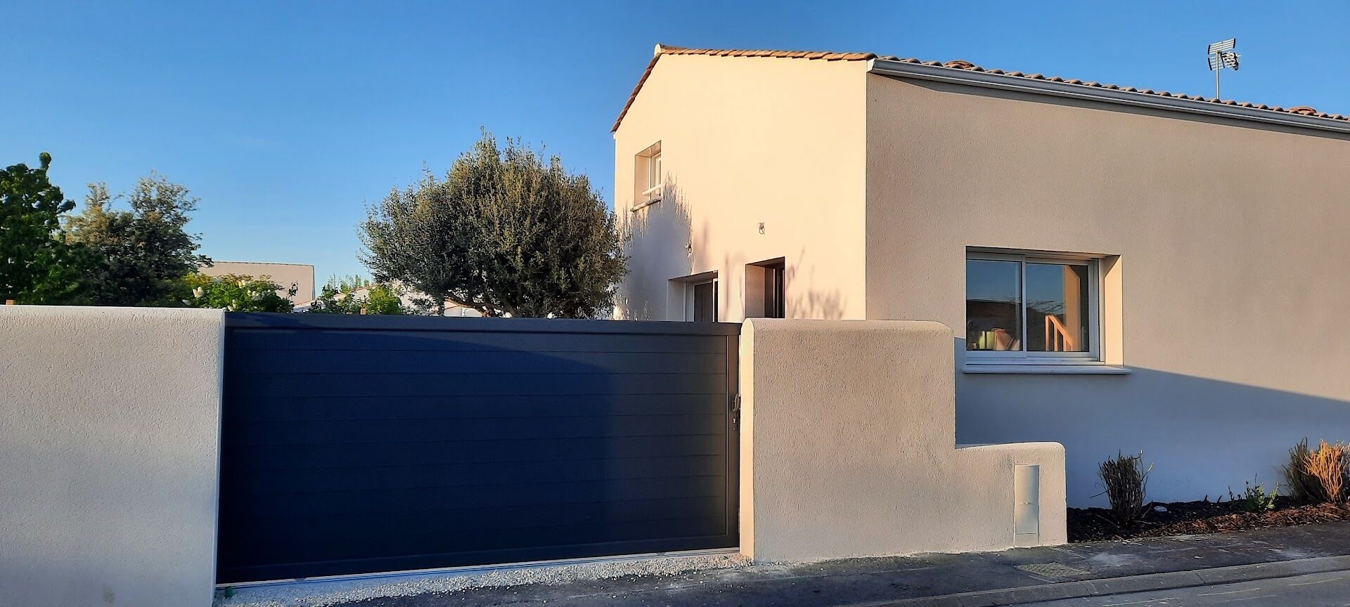 Un bâtiment moderne doté d’un garage fermé par une porte, d’une fenêtre et d’un petit balcon.