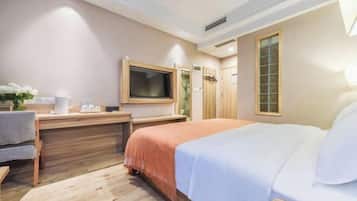 Una habitación de hotel con cama, escritorio, televisión y ventana.