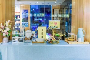A hotel reception area with a glass partition, a reception desk, a vase with flowers, a tea set, and a sign with Chinese characters. - Seaman Hotel (Chongqing Jiazhou Hongqi Hegou Light Rail Station) (Chongqing)