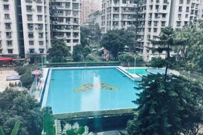 A swimming pool with a lily pad design, surrounded by greenery and high-rise buildings. - Seaman Hotel (Chongqing Jiazhou Hongqi Hegou Light Rail Station) (Chongqing)