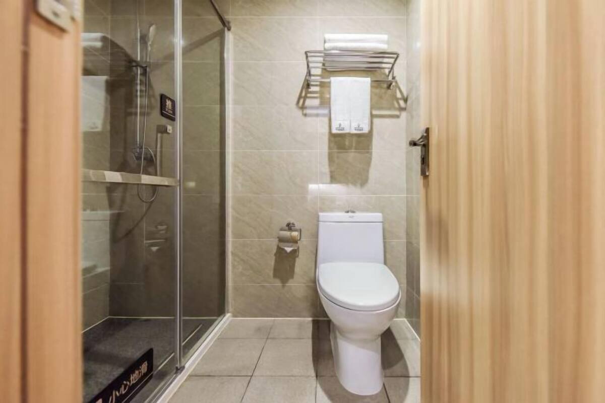 A bathroom with a glass shower enclosure, a toilet, and a towel rack.