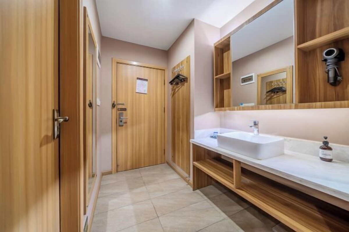 A bathroom with wooden cabinets, a white sink, and a large mirror.