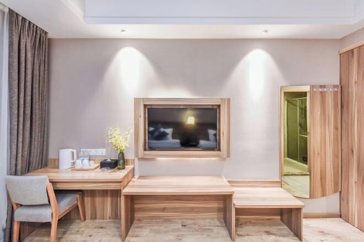 A modern room with a wooden desk, a chair, a small table, a window, and a mirror.