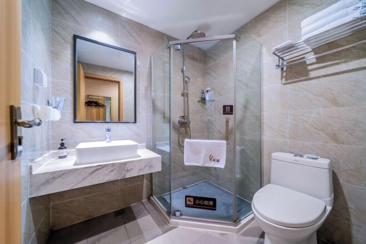 A modern bathroom with a glass-enclosed shower, a white sink, and a toilet.