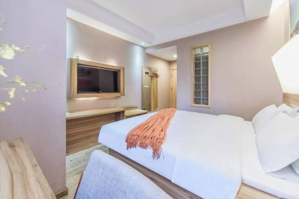 A modern bedroom with a large bed, a television, and a window.