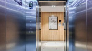 An elevator interior with a wooden panel wall, a door with a number sign, and a small poster on the wall. - Seaman Hotel (Chongqing Jiazhou Hongqi Hegou Light Rail Station) (Chongqing)