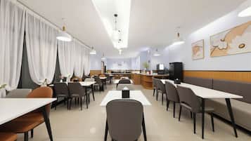 Un comedor moderno con mesas, sillas, una barra y un televisor.