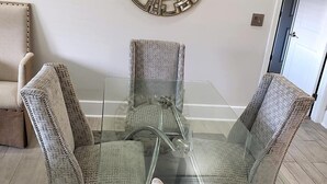 Comedor con una mesa de vidrio rodeada de sillas estampadas.