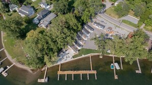 Luchtbeeld van een landgoed aan een meer met een steiger, huizen en een parkeerplaats.