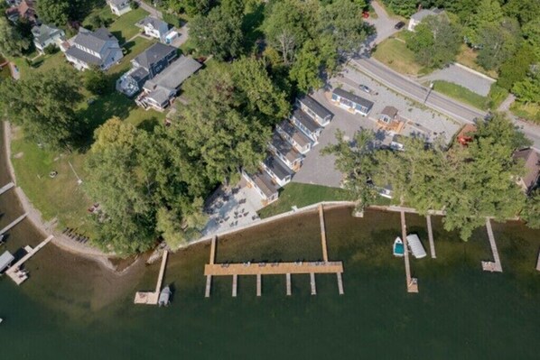 An aerial view of a lakeside property with a dock, houses, and a parking area.