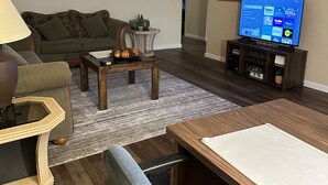 Un soggiorno con divano, tavolino, televisione e tavolo da pranzo con sedie.