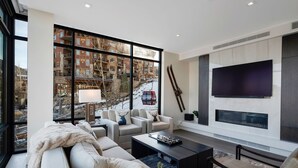 Ein modernes Wohnzimmer mit großem Fenster, Flachbildfernseher und Kamin.