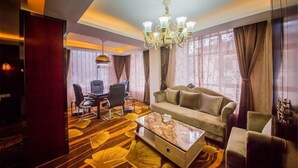 Una sala de estar moderna con sofá, mesa de centro y sillas. Se observa una araña y un comedor con mesa y sillas.